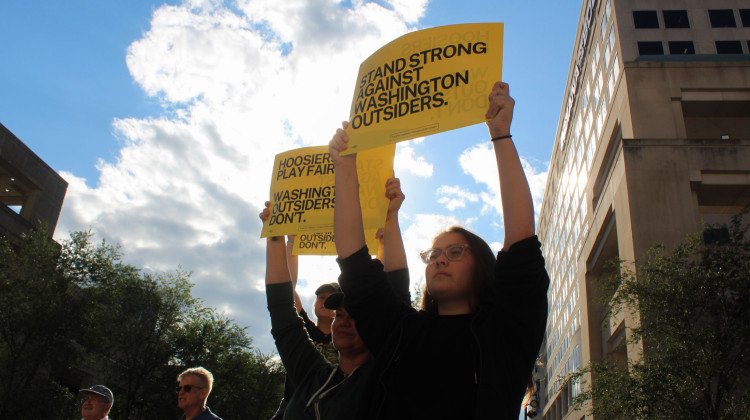 Protesters hold signs against President Donald Trump’s push to redistrict Indiana congressional districts at the Indiana Statehouse on Tuesday, Aug. 26, 2025. The crowd gathered the same day some Republican state lawmakers visited the White House. - Farrah Anderson / WFYI