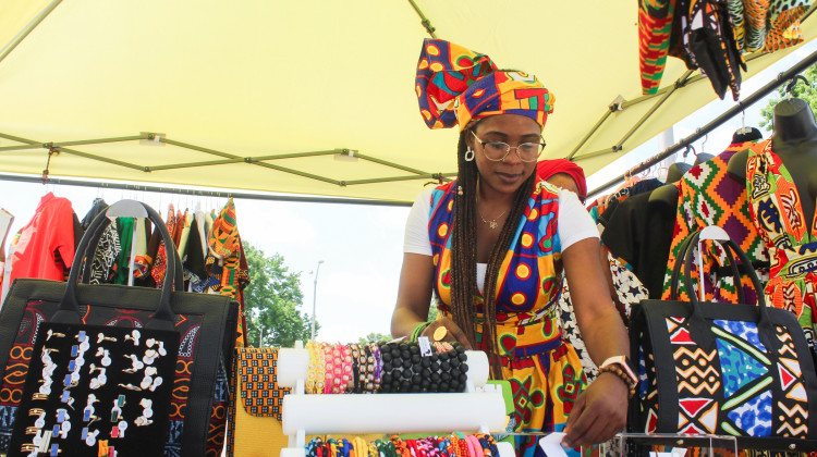 Laila Saahir, an Indianapolis resident, arranges her items as a vendor at the Indy Juneteenth event on Saturday, June 21. Saahir, who is originally from Cameroon, owns Afrikan Authentix, an online clothing boutique that sells handmade African clothing and accessories. - Farrah Anderson / WFYI