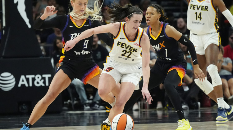 Indiana Fever guard Caitlin Clark (22) is defended by Phoenix Mercury guards Sophie Cunningham (9) and Sug Sutton (1) during the second half of a WNBA basketball game Sunday, June 30, 2024, in Phoenix. - Ross D. Franklin / AP Photo