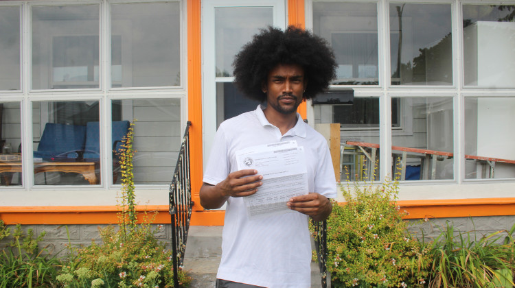 Mulugeta Wolfe holds up letters he’s received from the state about his Healthy Indiana Plan coverage. He said he’s received no direct communication about a pause in monthly payments. - Ben Thorp / WFYI