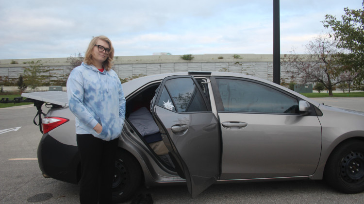 Ryan Warner stands in front of his car where he lives. He’s says finding a place to park for the night is a regular source of stress - Ben Thorp / WFYI