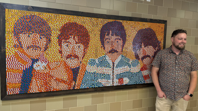 Artist Corey Heimann stands next to a permanent art installation of the Fab Four at the Indiana Farmers Coliseum. - Jill Sheridan / WFYI