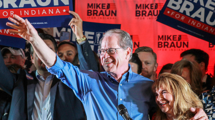 Mike Braun, with one arm wrapped around his wife Maureen, waves to a crowd of supporters at his primary election night celebration on May 7, 2024. - Brandon Smith / IPB News