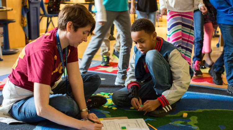 A teacher reviews a student’s completed work in a third-grade classroom as students rotate to new math stations. - Allison Shelley/The Verbatim Agency for EDUimages