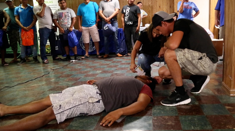 Miriam Sonderborg of the nonprofit Proteus shows farm workers how to care for someone who has passed out from the heat using volunteers at a training in 2022. - Devan Ridgway / WTIU